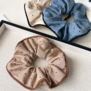 Detailed close-up of three vintage polka dot fabric scrunchies in beige, blue, and khaki
