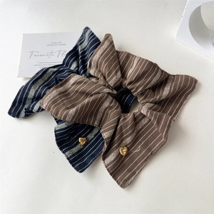 Detail view of retro striped scrunchies in navy and brown with golden heart charms