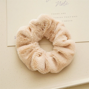 Dettaglio macro dell'elastico per capelli in peluche beige con texture morbida