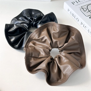 Détail des chouchous surdimensionnés en similicuir noir et marron avec coutures fines