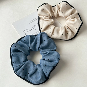 Detail of retro polka dot hair scrunchies in beige and blue denim fabric with black piping