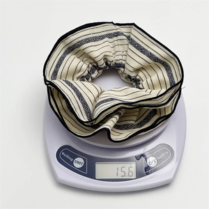 Detail view of a striped fabric scrunchie on a digital scale showing weight of 15.6g
