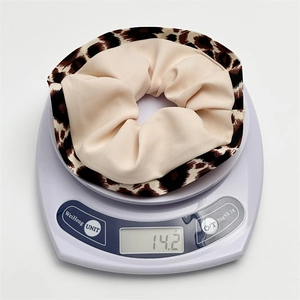 Detailed top view of leopard print scrunchie on scale showing weight of 14.2 grams