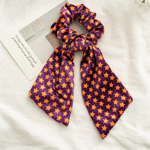 Dettaglio dell'elastico per capelli in velluto Halloween con stelle e nastri viola e arancio