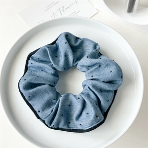 Close-up of blue denim scrunchie with black rhinestones on a white ceramic plate