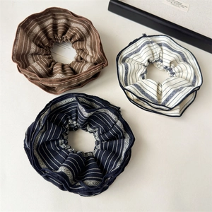 Three-pack retro striped fabric scrunchies in brown, beige, and navy for ponytails