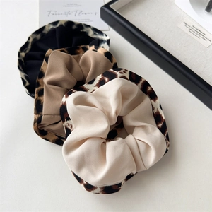 Detailed view of leopard print scrunchies in black, khaki and beige colors