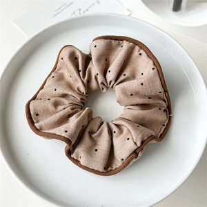 Detail of khaki polka dot scrunchie with brown piping on a white decorative tray