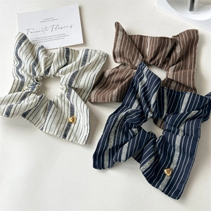 Three striped fabric scrunchies in cream brown and navy with heart metal charm