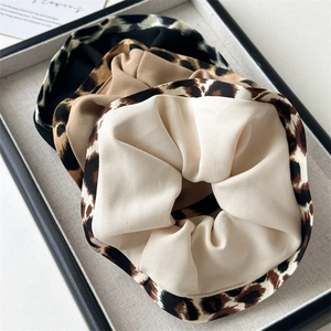 Detail of leopard print, khaki, and black ruffled scrunchies set in a display tray