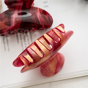 Detailed macro view of large marble texture acrylic hair claws on a white magazine