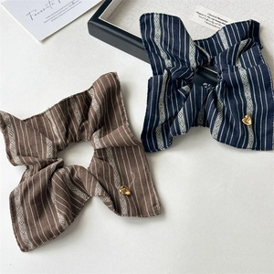 Close-up of striped vintage hair scrunchies with decorative heart-shaped gold buckles
