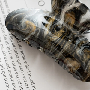 Detailed close-up of marble pattern acrylic hair claw with silver glitter texture