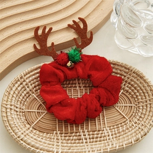 Detail of red velvet Christmas scrunchie with reindeer antlers and golden bell decoration