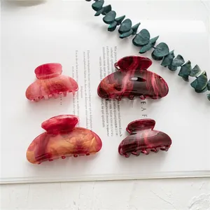 Detailed view of four acetate marble hair claw clips in burgundy and amber patterns