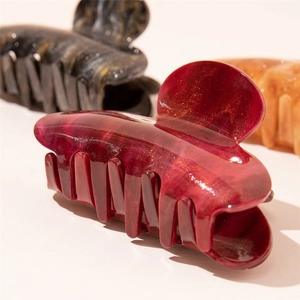 Detail of large acrylic claw clips in marble red and amber with gold glitter finish