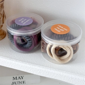 Close-up of hair ties and spiral coils in two transparent gift jars with purple labels