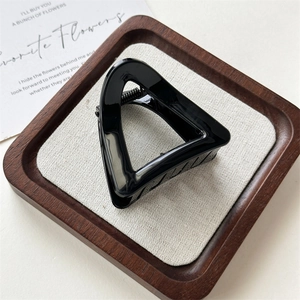 Gros plan d'une pince à cheveux triangulaire noire brillante au design géométrique chic