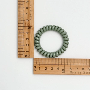 Detailed size measurement of a 5cm grey-green spiral phone cord hair tie with rulers