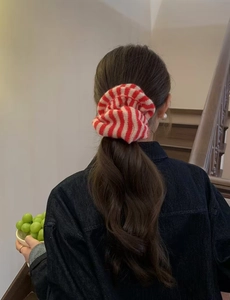 Detail of red and white striped knitted hair scrunchie shown on a ponytail hair style