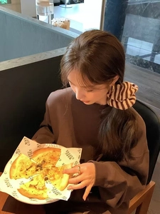 Brown striped knit oversized scrunchie hair accessory shown in a cozy cafe setting
