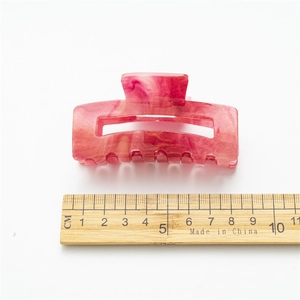 Pink marbled acrylic hair claw with gold glitter finish measuring 8.5cm on white base