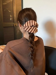 Close-up of knit striped hair scrunchie in brown and beige on a braided hairstyle