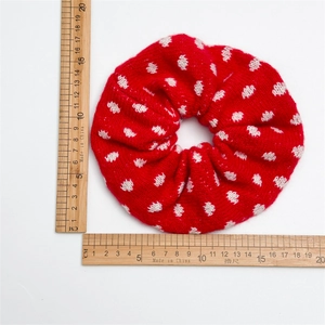 Oversized red knit scrunchie with white heart pattern being measured on white background