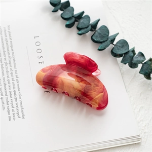 Detail of red marble texture acetate hair claw clip on a minimalist lifestyle background