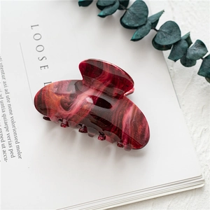 Detail of red marble acrylic hair claw clip with golden glitter on a magazine page