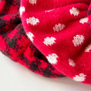 Close-up of red knit hair scrunchie with black checkerboard and white polka dot texture
