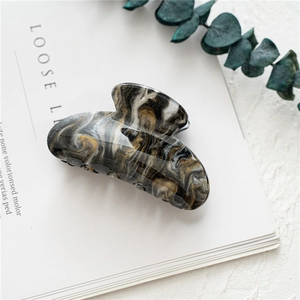 Macro shot of large acrylic hair claw clip with black and gold marble texture on magazines