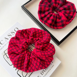 Close-up of red and black knitted scrunchies with houndstooth and diamond grid patterns