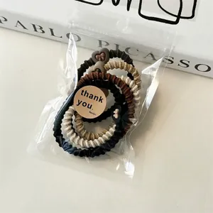 Gros plan d'élastiques à cheveux spirales aux tons terre dans un sachet cadeau
