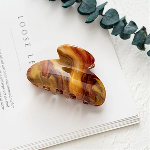 Detail of amber marble hair claw clip with glossy finish on a minimalist background