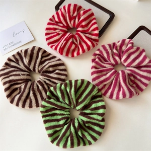 Flat lay of striped knit hair scrunchies in various colors on a wooden tray