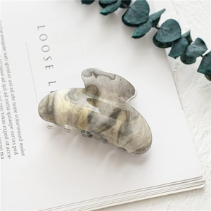 Macro view of large acrylic hair claw clip with grey and gold starry marble texture