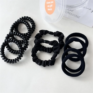 Detail of 10-piece black hair tie set with spiral cords and scrunchies in a clear jar