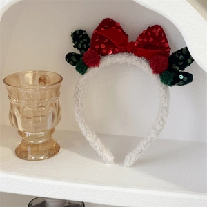 Detail of Christmas headband with red velvet sequin bow and green antler accents