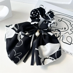 Detail of elegant black and white floral ribbon scrunchie with pearl and bow charm decor