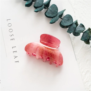 Detail of pink marble claw clip with gold glitter and acetate texture on white background