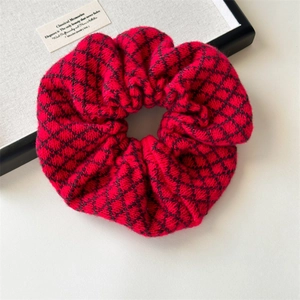 Detailed close-up of a red knitted scrunchie with diamond patterns and warm yarn texture