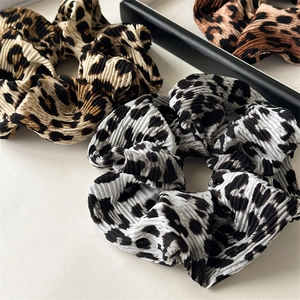 Detailed close-up of leopard print hair scrunchies showing pleated fabric texture