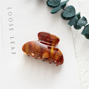 Top view of a large brown amber marble hair claw clip with golden glitter on a white book