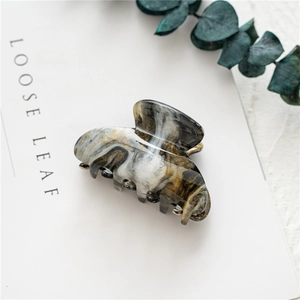 Detail of large acrylic marble hair claw with gold glitter flakes on a white card