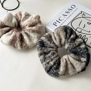 Close-up of soft woolen scrunchies in beige and brown textures on an aesthetic book