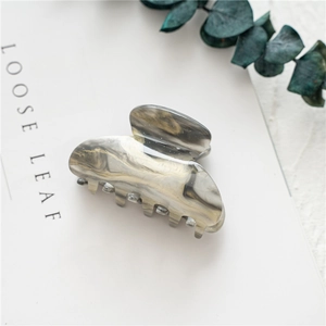Detail of large acrylic shark hair claw with marble texture and glitter finish