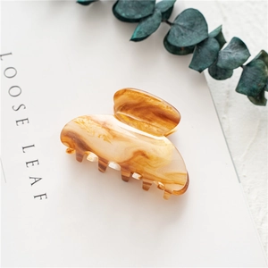 Detailed view of amber tortoise shell hair claw clip on minimalist white background