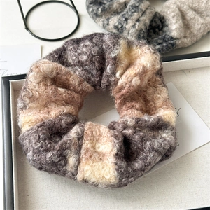 Detailed texture of a soft plush wool scrunchie in warm brown and beige patchwork colors