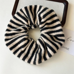 Close-up of a black and white striped knitted scrunchie with soft yarn texture details